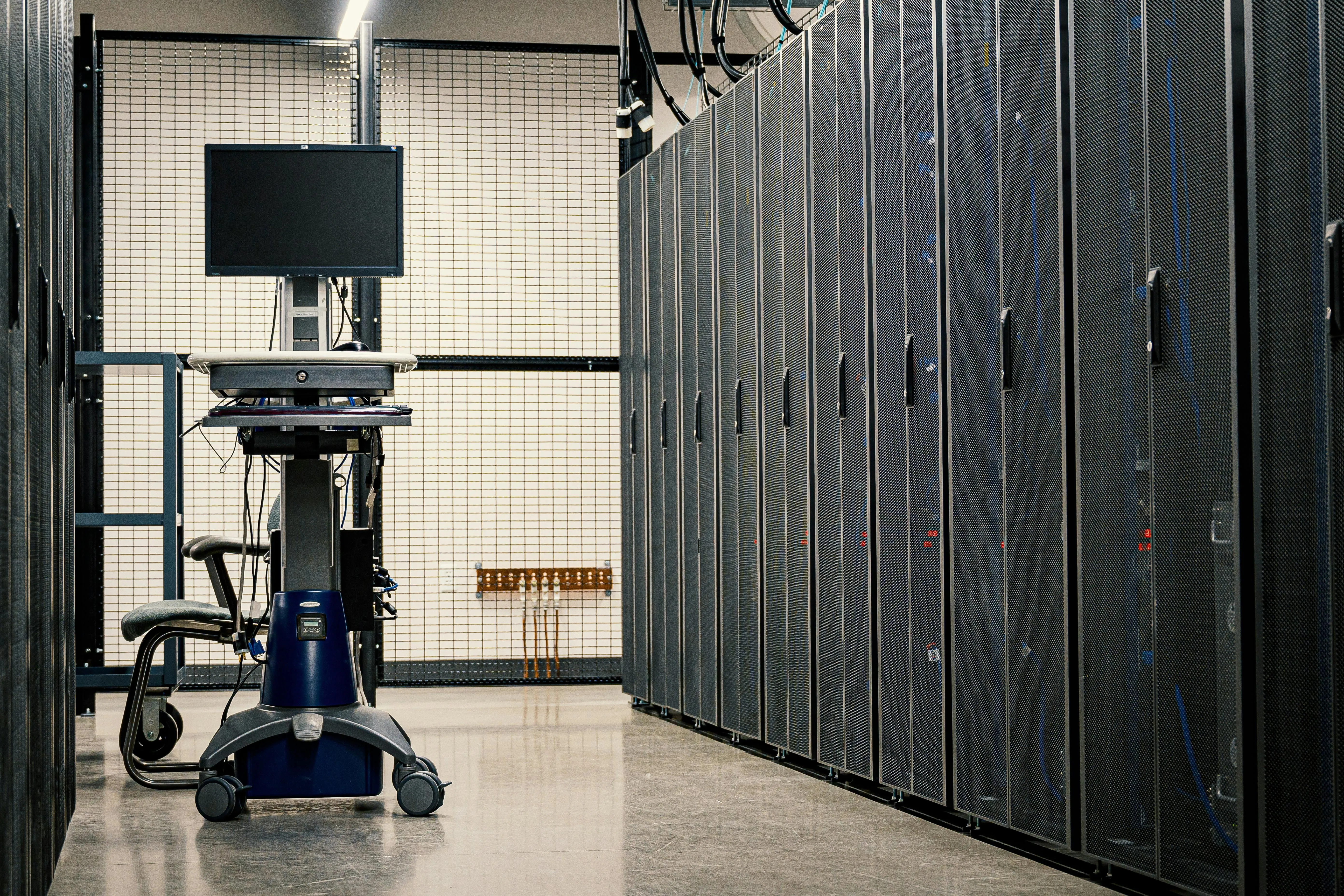 Mobile workstation with a monitor in a data center aisle lined with server racks.